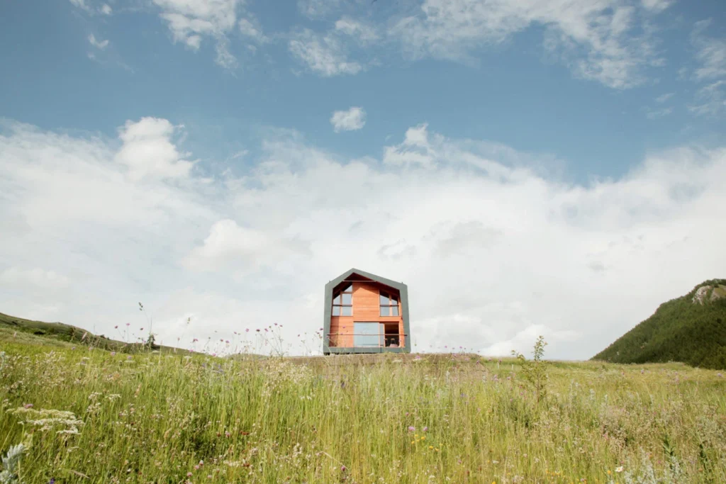 BIG - Prefabricated wooden house immersed in a green grassy field